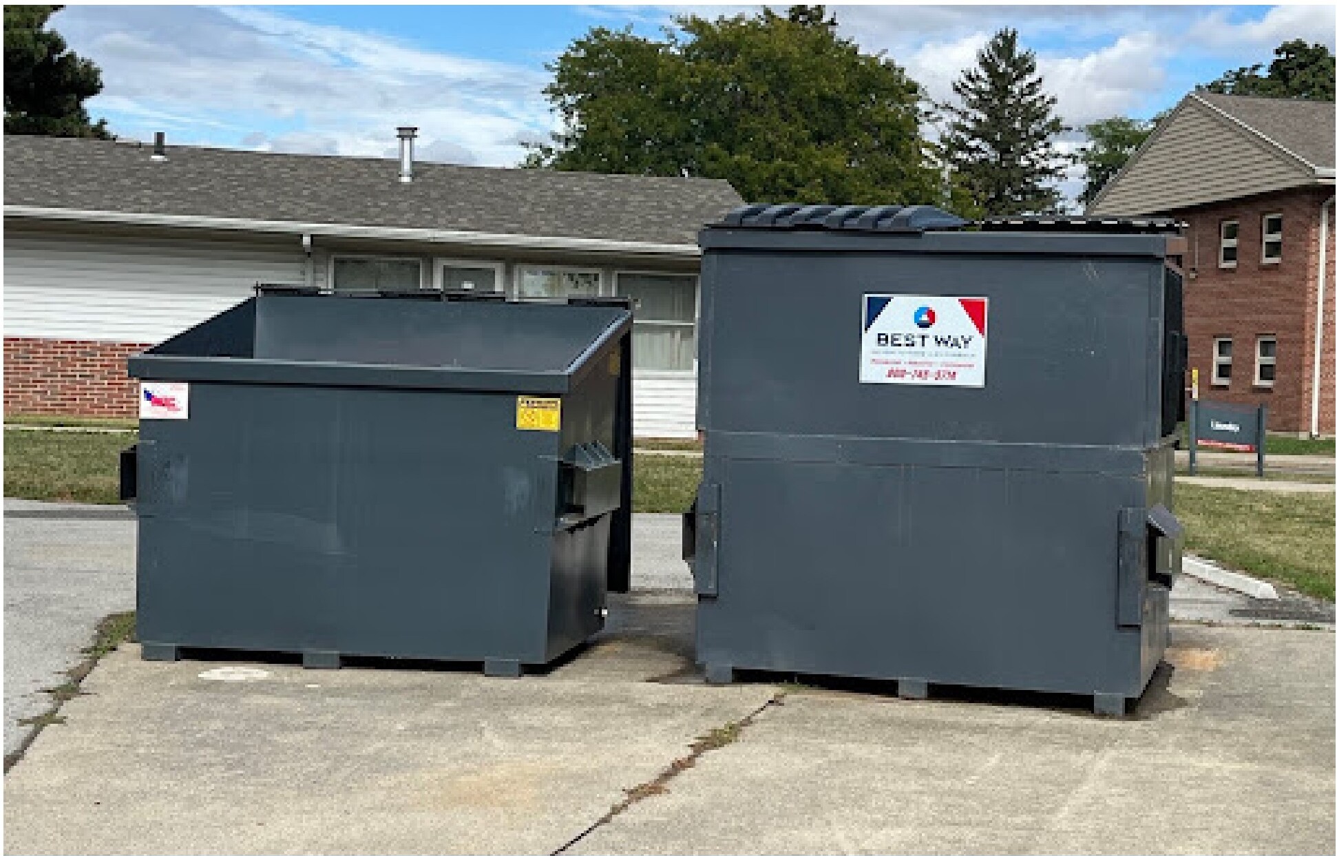 Two near-identical dumpsters outside Scheidler apartments with poor signage, making recycling and trash visually indistinguishable.