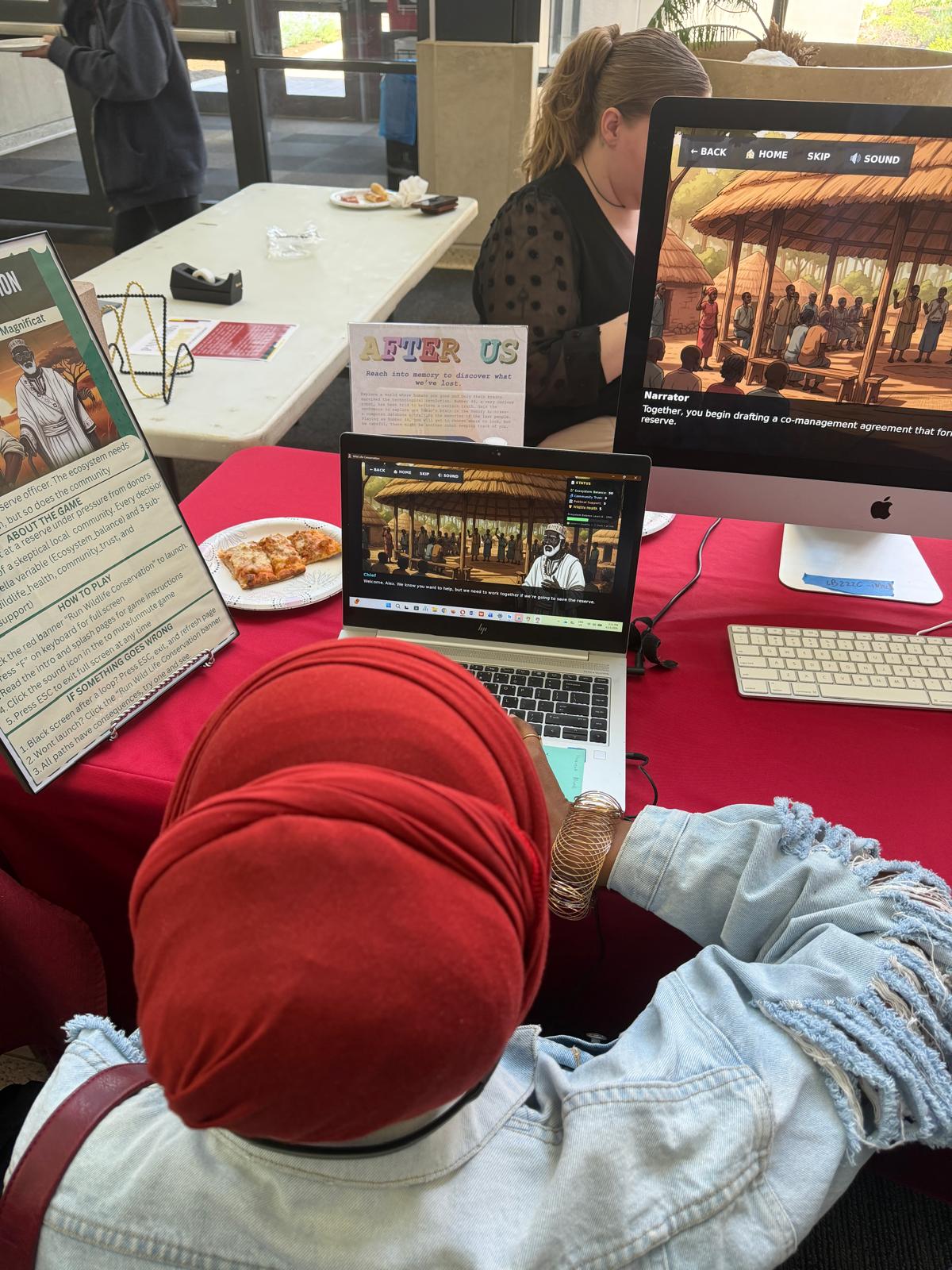 A playtester reading the game's How to Play card while playing on a laptop at the showcase